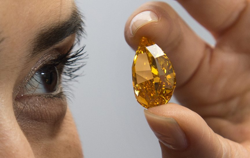 A Christie’s employee displays the 14.82-carat pear-shaped orange diamond that was auctioned off Tuesday in Geneva.