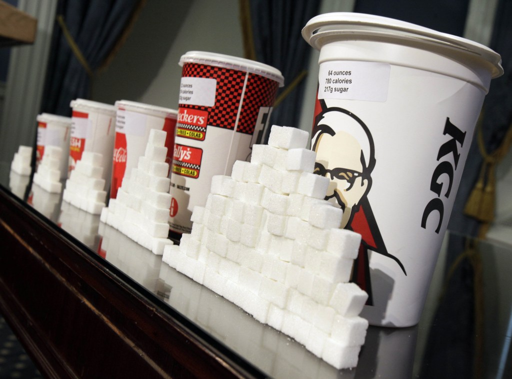 This May 31, 2012 file photo shows a display of various size soft drink cups next to stacks of sugar cubes at a news conference at New York’s City Hall. It’s one of our most personal daily decisions: what to eat or drink. Maybe inhale. Does banning trans fat from our food mean the government is getting serious about cracking down on all sorts of other unhealthy stuff: Soda? Salt? Cigarettes? Alcohol? Probably not. In fact, in some states, they’re easing the way for marijuana.