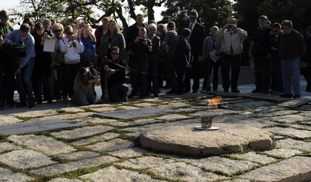 People visit the eternal flame at the gravesite of former President John F. Kennedy as it burns at Arlington National Cemetery in Arlington, Va. President Barack Obama will visit the gravesite of John F. Kennedy and pay tribute to two signature initiatives begun by the slain president as the nation observes the 50th anniversary of his assassination in the coming week.