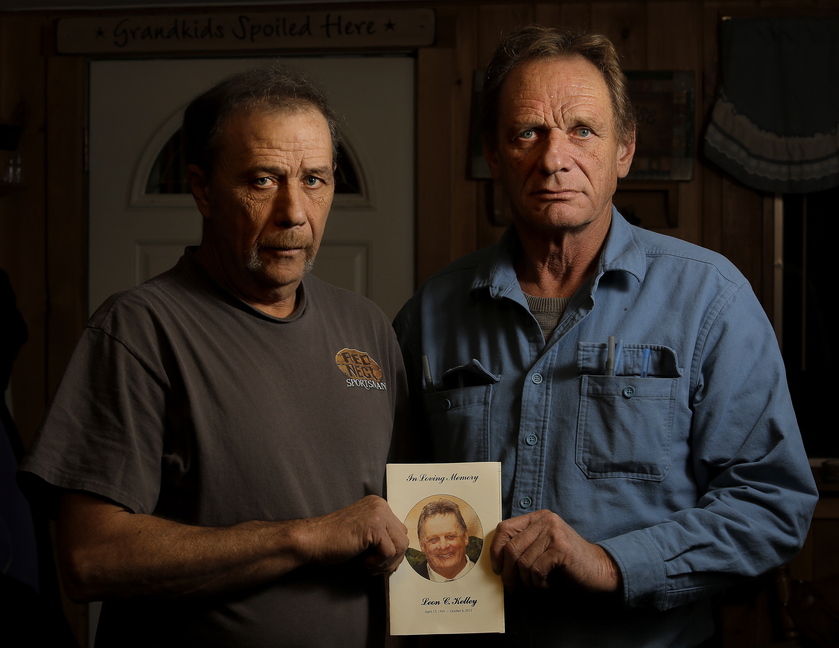 Brothers Joseph and William Kelley hold a picture of their deceased brother, Leon, while standing in the kitchen of Joseph's Woolwich home Wednesday. Leon Kelley was shot dead at a North Yarmouth bee farm last month, and Merrill “Mike” Kimball, 70, of Yarmouth was indicted on murder charges.