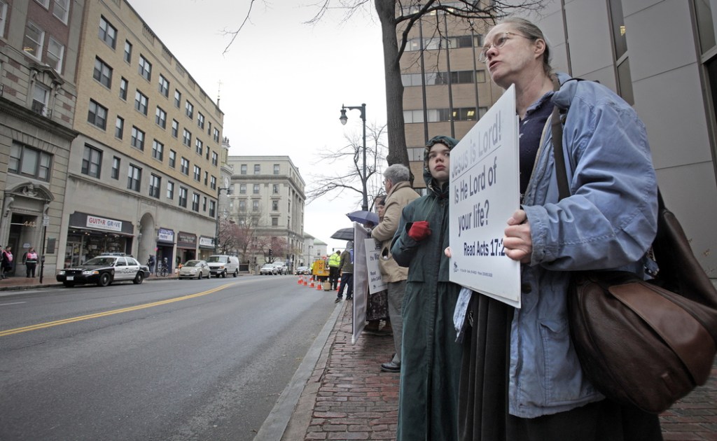 Marguerite Fitzgerald of Shapleigh stands with other anti-abortion protesters Friday across Congress Street from the Planned Parenthood clinic, where a Portland police car is parked. There is now a 39-foot buffer zone around the clinic.