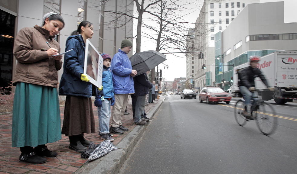 Anti-abortion protesters stand across the street from the Planned Parenthood clinic in Portland on Friday, the first day that protesters have picketed the Congress Street clinic since a 39-foot buffer zone around Planned Parenthood took effect.