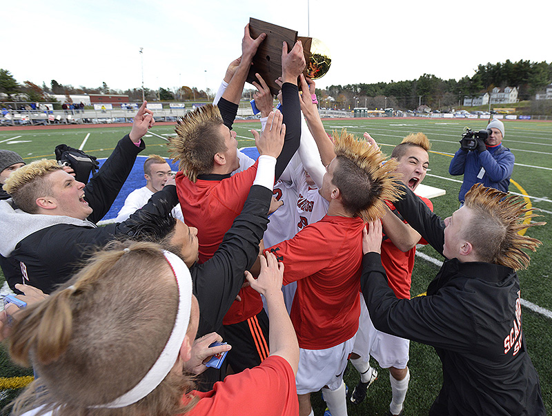 Members of the Scarborough boys’ soccer team hoist the trophy captured after a 2-1 win over Hampden Academy in the Class A state championship game on Saturday at McMann Field in Bath. BoysAsoccer