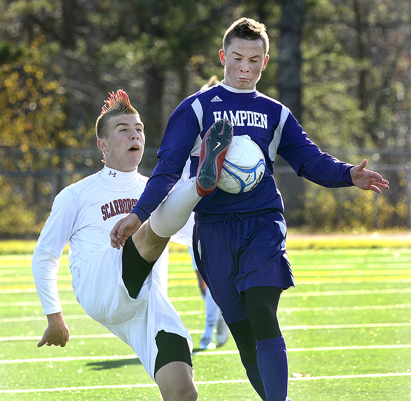 Scarborough’s Max Ornstein kicks the ball in front of Hampden Academy’s Noah Parker during the Class A state soccer final Saturday. Scarborough won in overtime, 2-1. BoysAsoccer