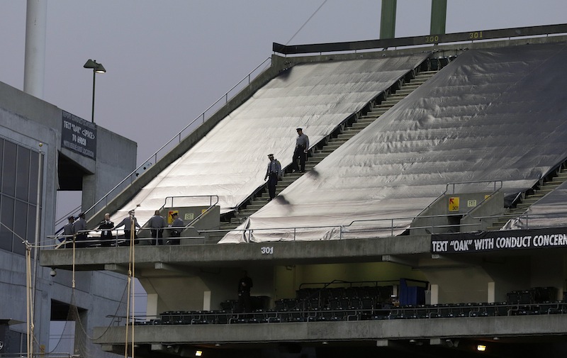 Law enforcement officials walk in the upper deck of O.co Coliseum after an NFL football game between the Oakland Raiders and the Tennessee Titans in Oakland, Calif., Sunday, Nov. 24, 2013. A woman who jumped from the third level of the Oakland Raiders' stadium survived after a man tried to catch her and broke her fall, authorities said. NFLACTION13;