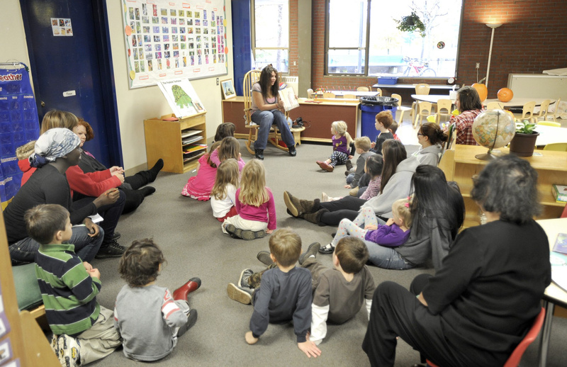 Preschoolers listen to their teacher read a story. Children who start learning earlier do better in school and in life.
