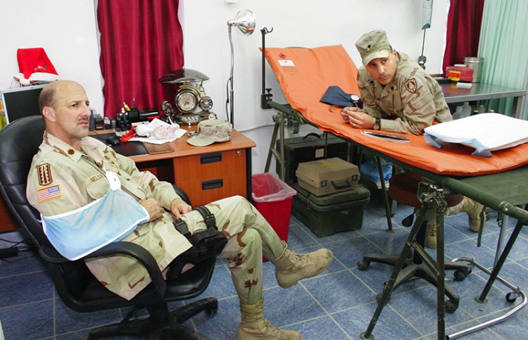 Staff photo by Gregory Rec -- Wednesday, December 22, 2004 -- Maj. John "Doc" Nelson, left, talks with medics Wednesday in the treatment room at the 133rd Engineer Battalion's aid station on FOB Marez. At right is Spc. Ronald Cyr of Lewiston. Maine soldiers injured in Iraq Maine soldiers killed in Iraq