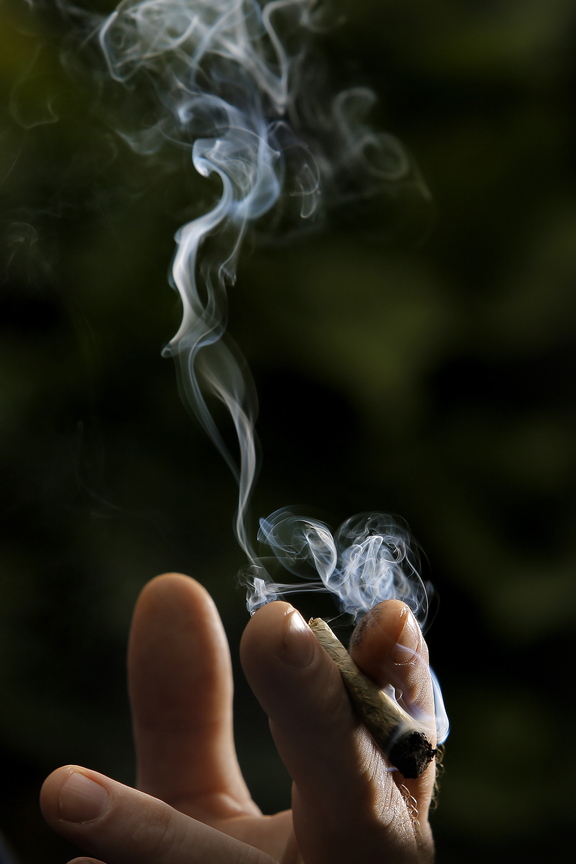 Smoke billows from a marijuana cigarette. A writer says that the state should not rush to legalize the drug.