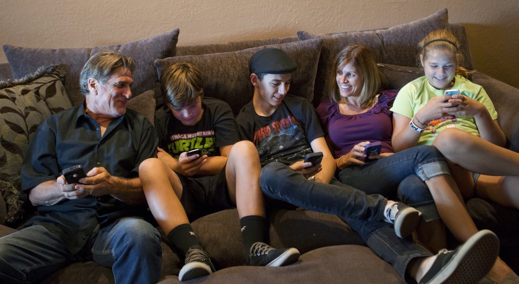 The Moore family, from left, Bill, Dylan, 13, Randy, 18, Sandra and Alyssa, 12, talk about how they use their smartphones, tablets and computers at their home in San Jose, Calif. “We spend a lot of time convincing Bill that it’s easier this way,” said his wife.