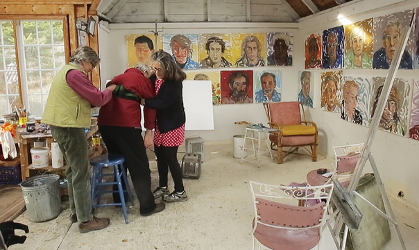 The artist’s wife, Jill Hoy, right, and a studio assistant, Holley Mead, assist Jon Imber as he prepares to work in his Stonington studio, where evidence of his latest burst of creative energy decorates the walls. Hoy described her husband, who has had to relearn to paint after ALS robbed him of first his right arm, then his left, as one of the most courageous painters she’s ever known. Since August, the artist has maintained a dizzying pace, creating more than 100 paintings.