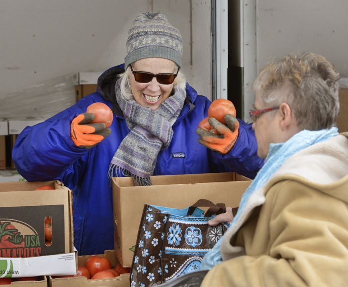 Volunteer Sheila O’Grady hands out tomatoes.
