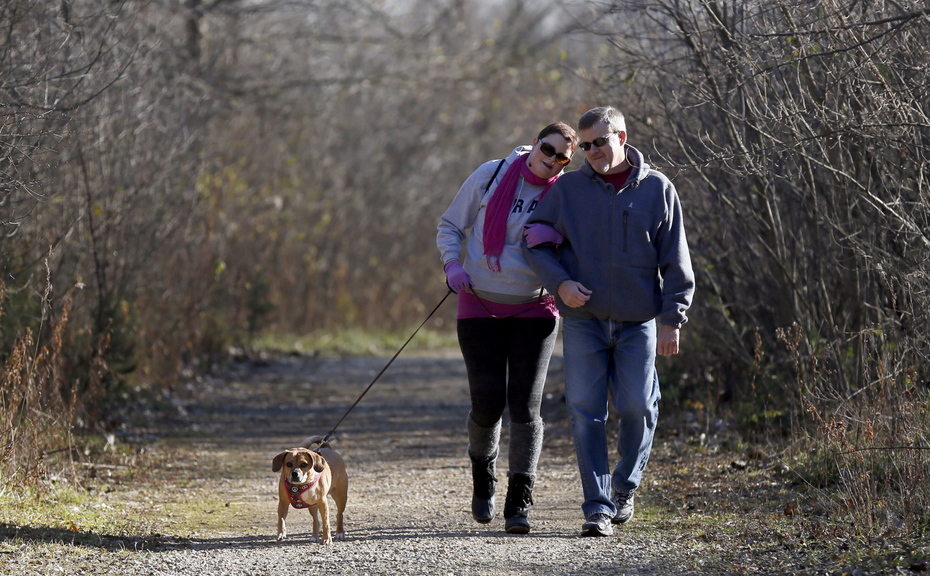 Meghan O’Brien, 31, left, takes a walk in the woods with her dad, Ken O’Brien, and their dog, Max, at Raceway Woods Forest Preserve in Carpentersville, Ill., Nov. 19. She is fighting both lung cancer and the condemnation that often comes with it.