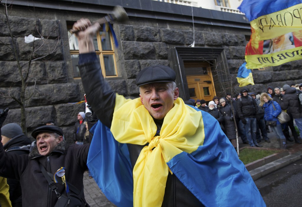 Protesters shout and wave flags marching toward government headquarters in Kiev, Ukraine, on Monday. Hundreds of Ukrainian protesters have blocked entrances to the government building and called for the ouster of the prime minister and his Cabinet.