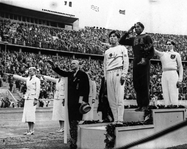 In this 1936 file photo, Olympic broad jump medalists salute during the medals ceremony at the Summer Olympics in Berlin. From left on the podium are: bronze medalist Jajima of Japan, gold medalist Jesse Owens of the United States and silver medalist Lutz Long of Germany.