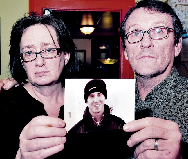 Lorna and Michael Smilek hold a photograph of Michael’s son, Justin Crowley-Smilek, a troubled U.S. Army veteran who was shot and killed by Farmington police in 2011.