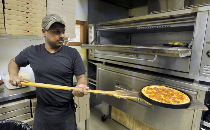 James Pyle of Falmouth slides a pizza from the oven at the Falmouth House of Pizza.
