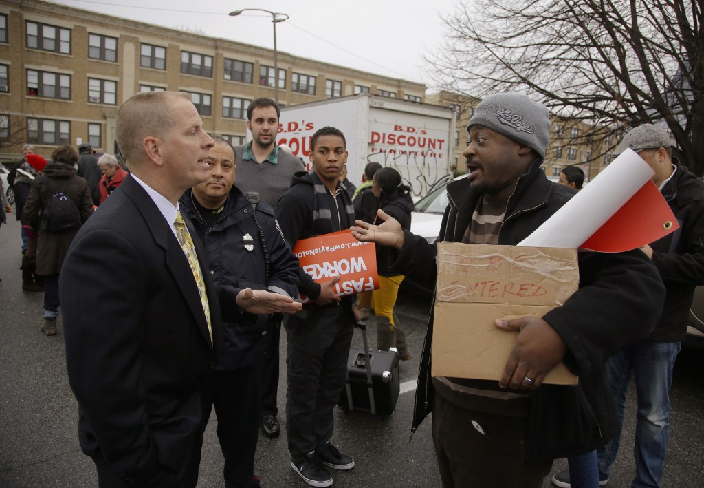 A man refusing to identify himself, left, confronts protest organizer Marlon Washington, right, before his group takes part in a nationwide protest supporting higher wages for workers in the fast-food industry and other minimum wage jobs at a Burger King restaurant in Boston on Thursday, Dec. 5, 2013 The unidentified man told Washington that his group had no right to be on the restaurant’s premises and threatened the towing of cars. No cars were towed.