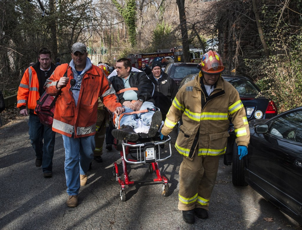 In this photo taken on Sunday, Metro North Railroad engineer William Rockefeller is wheeled on a stretcher away from the area where the commuter train he was operating derailed in the Bronx.