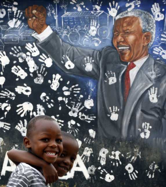 Two boys walk past a mural depicting former South African President Nelson Mandela at the Alexandra township in Johannesburg, South Africa, in this Dec. 11, 2012 file photo. On Thursday, Dec. 5, 2013, Mandela died at the age of 95.