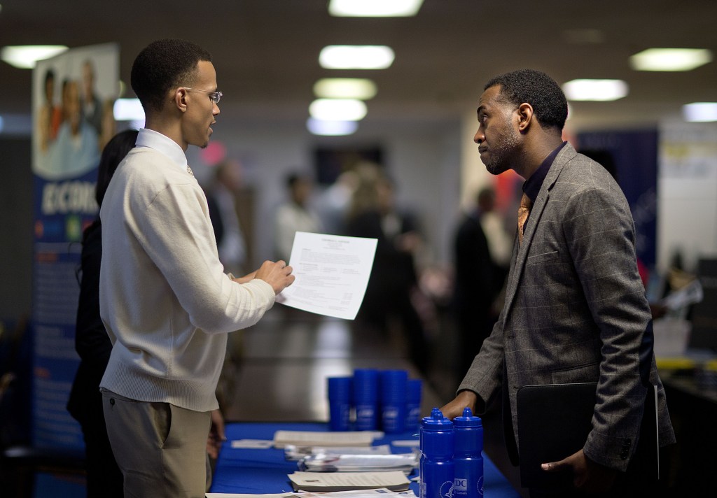 Retired Air Force Master Sgt. Thomas Gipson, right, of Atlanta talks about his resume last month with Ralph Brown, an analyst with the Centers for Disease Control and Prevention, during a job fair for veterans in Marietta, Ga. The U.S. job market is finally showing signs of consistent gains.