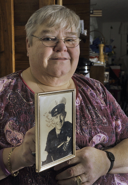 Jo Davis, above, holds a photograph of her late husband, Bert Davis, a Navy veteran who was at Pearl Harbor on Dec. 7, 1941.