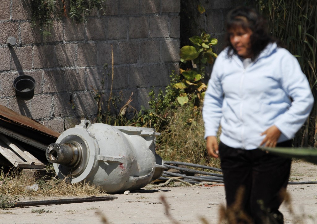A woman walks near part of a radiation therapy machine in the patio of the family that found the abandoned equipment in a nearby field in the village of Hueypoxtla, Mexico, on Thursday. Officials were engaged in the delicate task of recovering the stolen shipment of highly radioactive cobalt-60 abandoned in a rural field in central Mexico state.