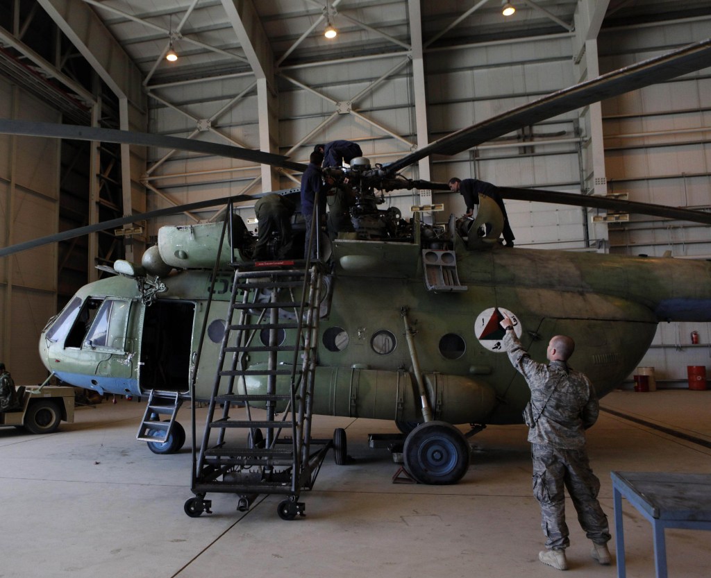 Sgt. Troy Bencke, right, points toward Afghan air force engineers as they work on an Mi-17 helicopter inside a hangar in Kabul, Afghanistan, in this April 6, 2010, file photo.