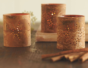 Cinnamon-bark tea lights with perforations in the bark let out the glow of candlelight.
