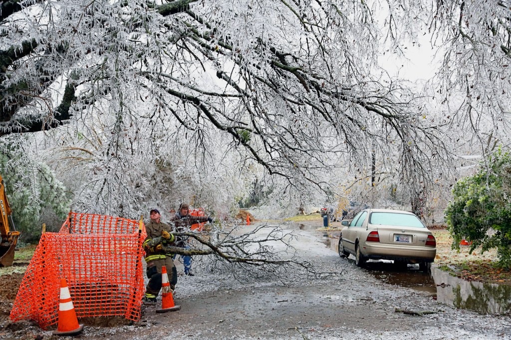 A Paris firefighter and a homeowner work together to clear debris from an ice storm in Paris, Texas, Friday, Dec. 6, 2013. A quarter of a million customers in North Texas were left without power, and many businesses told employees to stay home to avoid the slick roads. (AP Photo/The Paris News, Sam Craft)