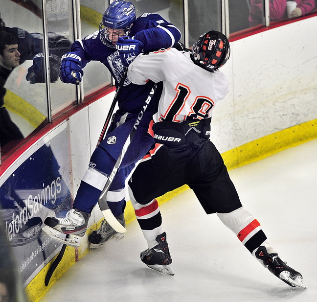 Max Bolduc of Lewiston gets checked into the boards by Biddeford’s Corey Brown during their boys’ hockey season opener Saturday afternoon at Biddeford Ice Arena. Lewiston won, 5-3.