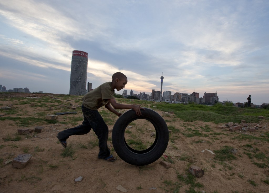 A boy plays with a rubber tire on a hill overlooking Johannesburg on Saturday. South Africa is no blissful paradise as it struggles with a staggering rate of violent crime. It has the world’s highest incidence of HIV infection. And it harbors a wide income inequality.