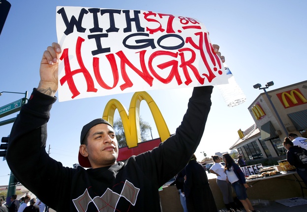 Alex Robles joins dozens of protesters at a rally against low wages for fast-food workers, in front of a McDonald’s in Phoenix last Thursday. Opponents invariably predict that raising the minimum wage will discourage employers from hiring, but recent research has found otherwise. Arizona’s minimum wage is $7.80 an hour; the minimum wage in Maine is $7.50.