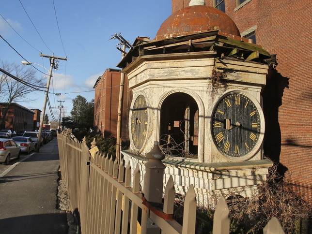 A historic clock tower rests on the ground next to the Lincoln Mill building in Biddeford, which it sat atop for 111 years before it was removed for safety reasons.