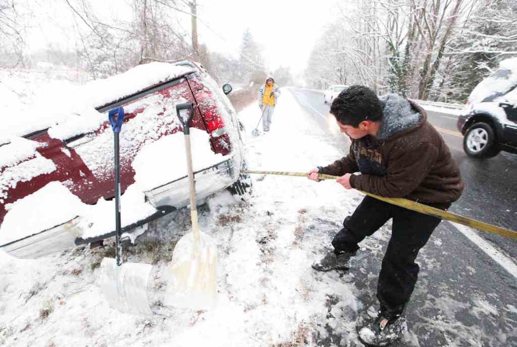 Juan Carlos tries to free his truck Sunday after it slid off Lancaster Pike in Wilmington, Del. The unexpectedly heavy snow led to a fatal crash in Pennsylvania involving 50 cars.