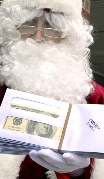 The Secret Santa displays a handful of envelopes containing $100 bills Friday. Since 2009, the generous businessman has given away $80,000 to brighten the Christmas season.