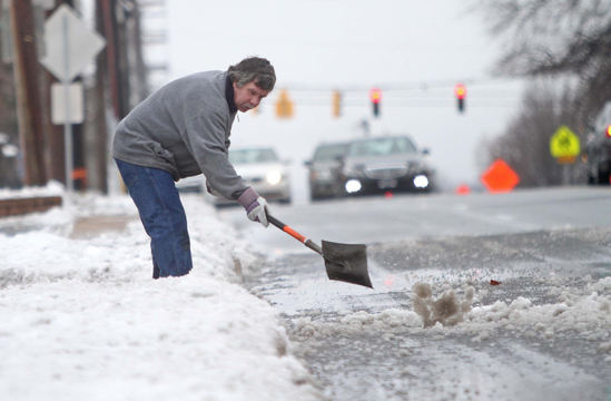 Jerry Lord clears snow from the shoulder of Lancaster Avenue in Wilmington, Del., on Monday. A storm that dumped heavy snow on the unsuspecting mid-Atlantic region left roads slippery and slushy in the Northeast for Monday’s commute.