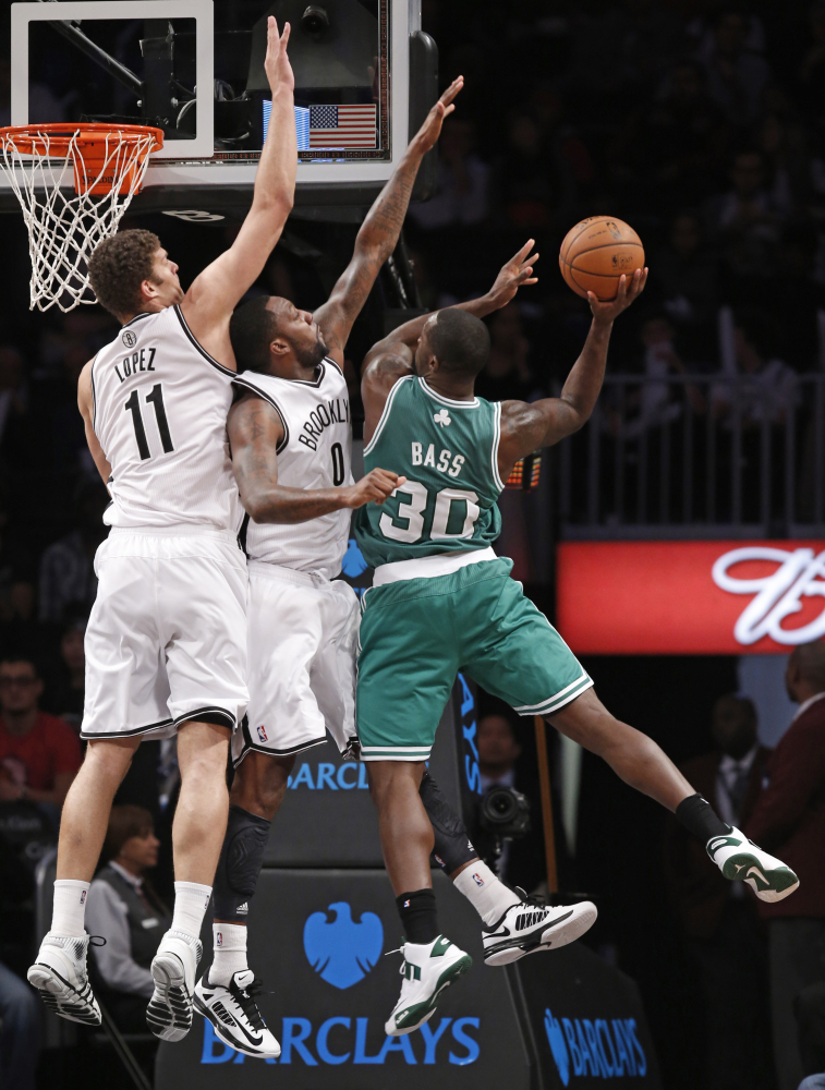 Brooklyn Nets Brook Lopez (11) and Brooklyn Nets Andray Blatche (0) defend Boston Celtics Brandon Bass (30) in the first half of their NBA basketball game, Tuesday, Dec. 10, 2013, in New York. (AP Photo/Kathy Willens)