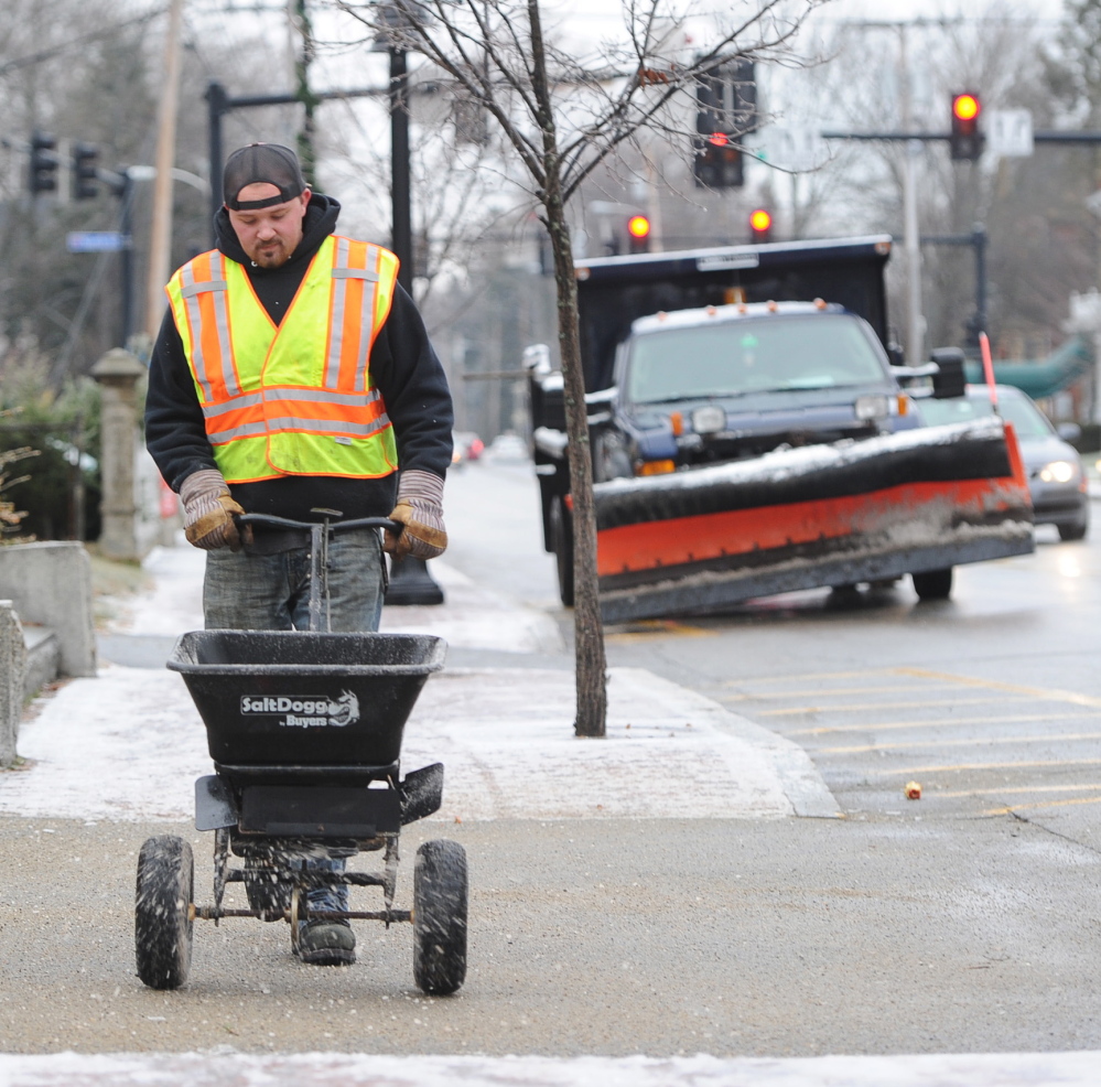 Saco Public Works employee Steve Aiken spreads salt on a Main Street sidewalk Tuesday after snow and sleet made for slick conditions throughout the region.