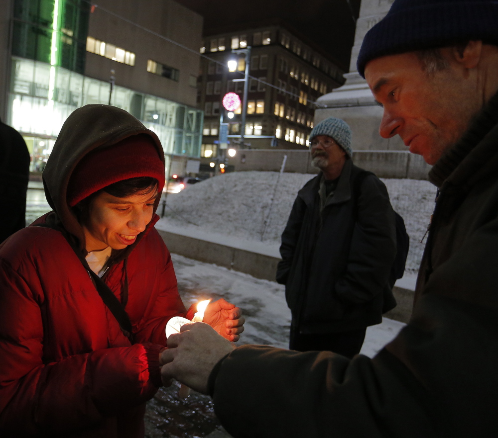 Liz Kramer of Portland has her candle lit by Ken Kohl, also of Portland, during a vigil in Monument Square on Tuesday in memory of the late South African President Nelson Mandela.
