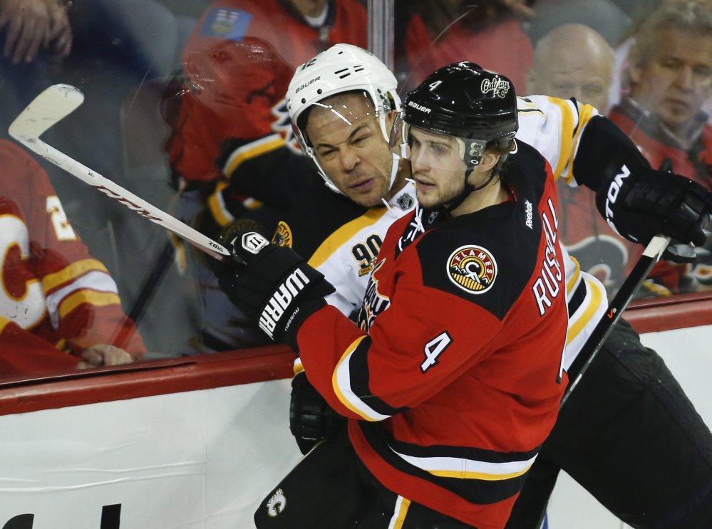 Boston’s Jarome Iginla, left, tries to get past the Flames’ Kris Russell during the second period of the Bruins’ 2-1 win at Calgary. The Flames honored Iginla before the game – his first in Calgary as an opponent.