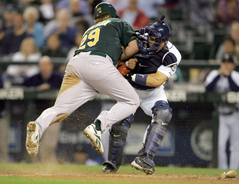 In this Sept. 27, 2006, file photo, Oakland Athletics’ Dan Johnson, left, collides with Seattle Mariners’ Kenji Johjima at home plate but was out on the play as Johjima held onto the ball in the ninth inning of a baseball game at Safeco Field in Seattle. New York Mets general manager Sandy Alderson, chairman of the rules committee, announced Wednesday, Dec. 11, 2013, that Major League Baseball plans to eliminate home plate collisions. He said player health and increased awareness of concussions were behind the decision.