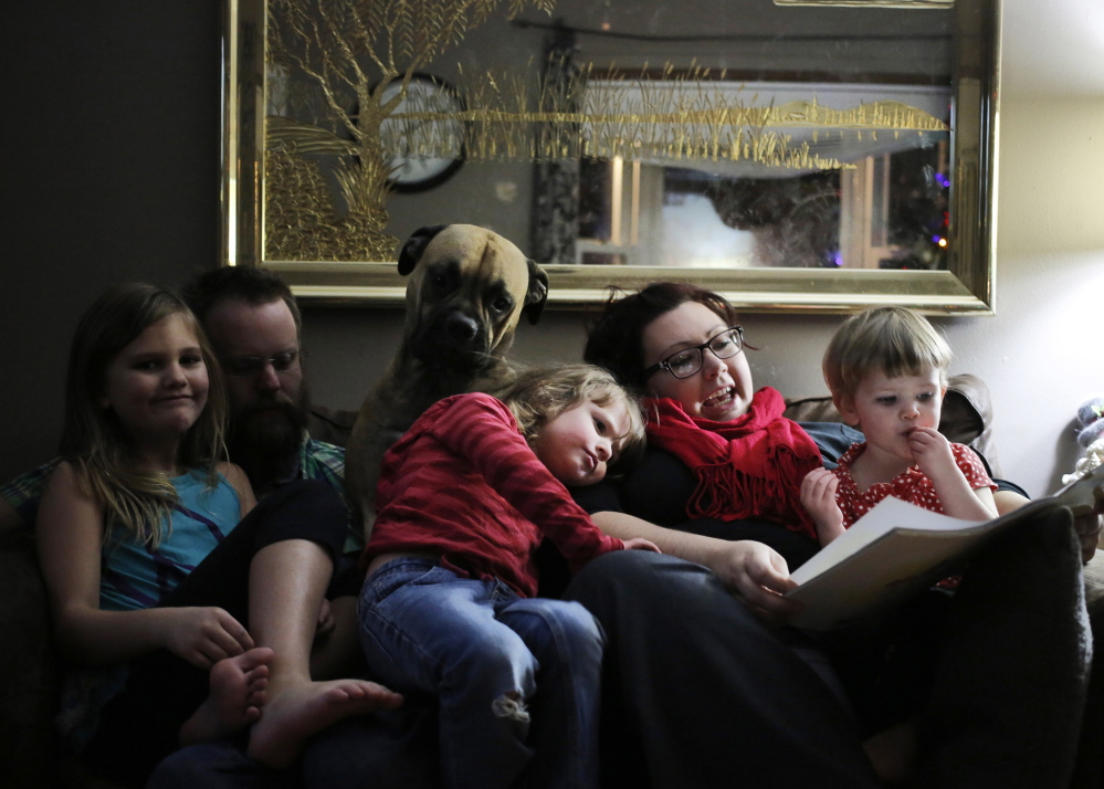 Carli Hopkins, 4, rests her head on mother Rebecca Hopkins, who is telling a story as Carli’s sister Violet, father Jason Hopkins, bull-mastiff Coco and younger sister River listen. Carli was on the losing end of the sequestration list.