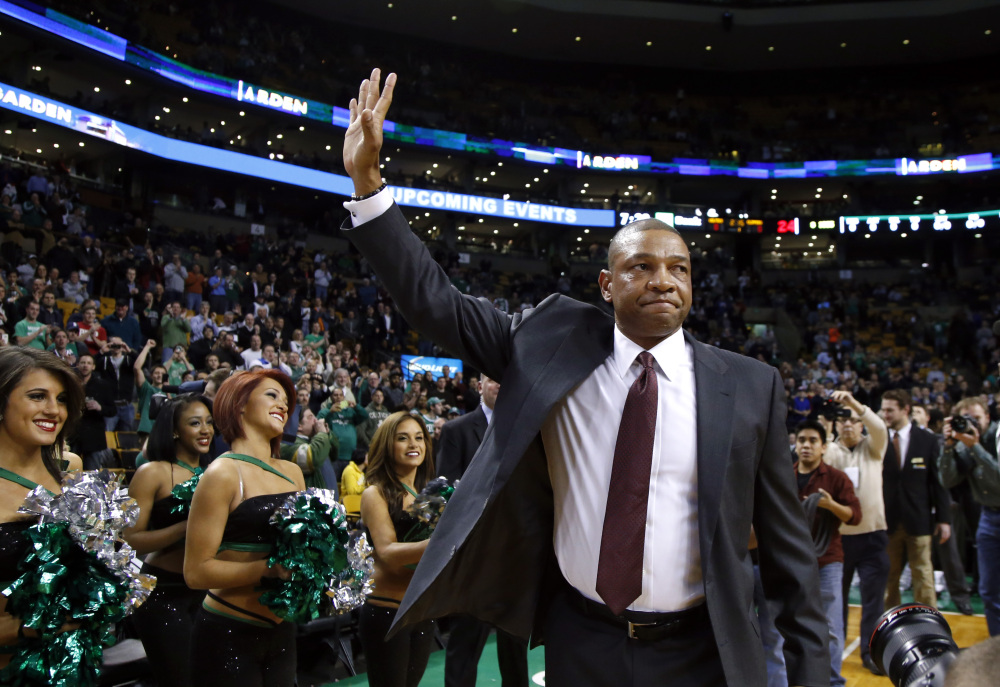 Doc Rivers, former head coach of the Boston Celtics and current head coach of the Los Angeles Clippers, waves to cheering fans as he enters the TD Garden floor for his first time back, before an NBA basketball game in Boston on Wednesday.
