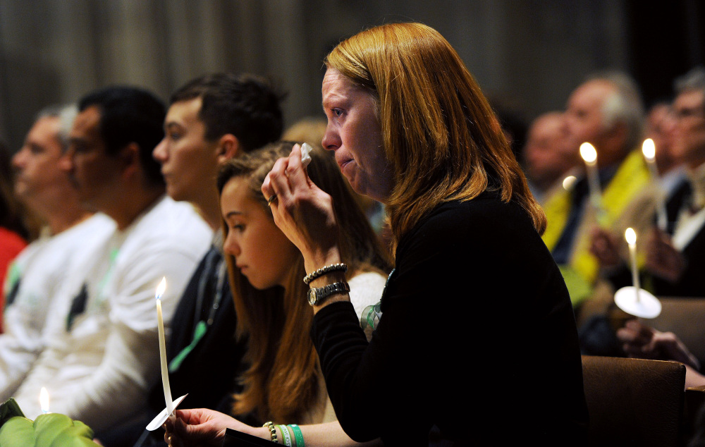 Miranda Pacchiana, center, of Newtown, Conn., wipes her eye during a National Vigil for Victims of Gun Violence at Washington National Cathedral in Washington on Thursday, two days before the first anniversary of the Sandy Hook Elementary School mass shooting. Federal gun laws remained unchanged after the furor died down, leaving states to act.