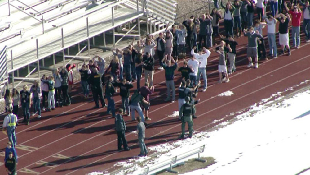 In this image taken from video provided by Fox 31 Denver, students gather just outside of Arapahoe High School as police respond to reports of a shooting Friday.