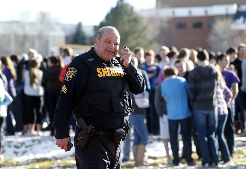 A sheriff deputy talks on his radio at Arapahoe High School in Centennial, Colo., on Friday. A student shot two other students before killing himself, authorities said.