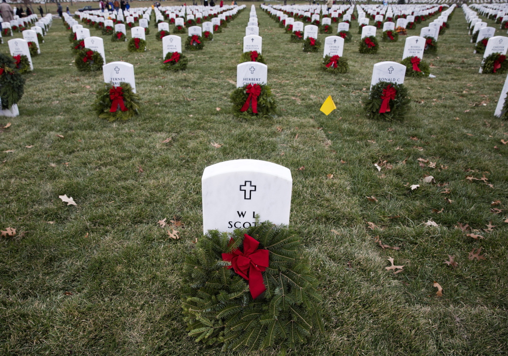 Remembrance wreaths from Maine rest in front of graves at Arlington National Cemetery in Washington on Saturday, National Wreaths Across America Day. Volunteers and families of the fallen placed thousands of the wreaths on headstones throughout the cemetery.