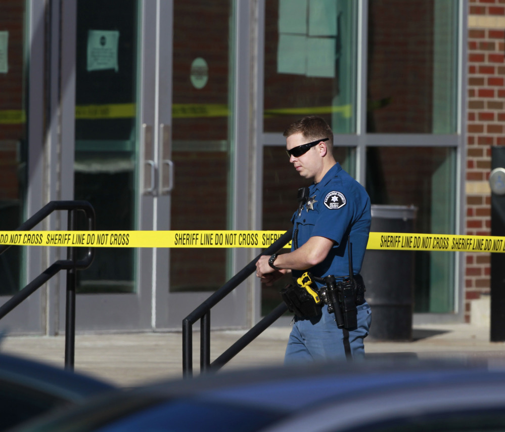 A deputy of the Arapahoe County (Colo.) Sheriff’s Department walks past crime scene tape Saturday at Arapahoe High School in Centennial, Colo. The student who killed himself was angry with the debate coach.