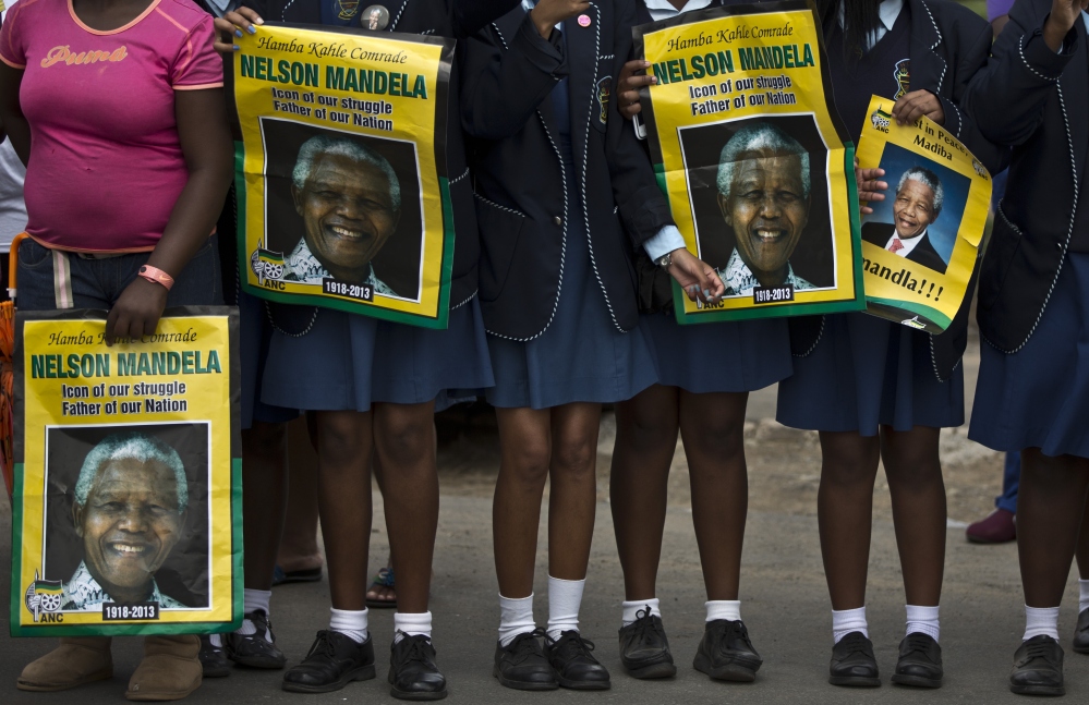 South African schoolgirls hold posters of Nelson Mandela as they wait for the former president's casket Saturday.