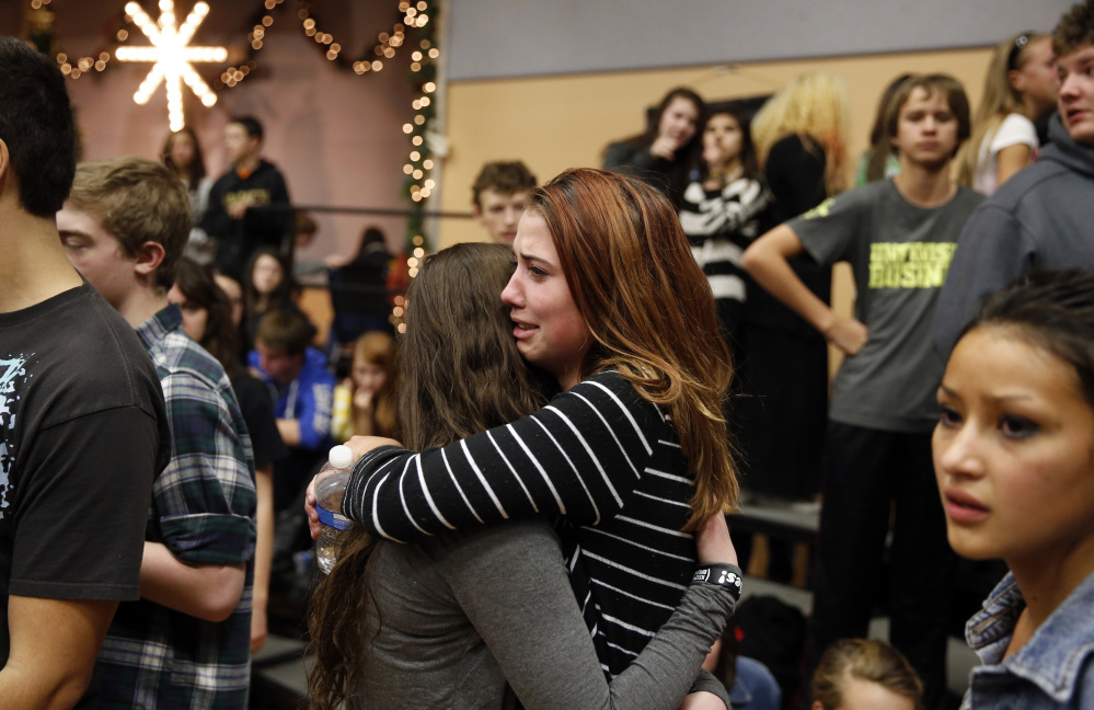 Freshman Allie Zadrow, center right, hugs classmate Liz Reinhardt at a church after a shooting at nearby Arapahoe High School in Centennial, Colo., on Friday, Dec. 13, 2013. Students from the school were evacuated to the church. Arapahoe County Sheriff Grayson Robinson said the shooter shot two others at the school, before apparently killing himself.
